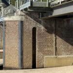 Bakstenen brug met metalen constructies boven water.