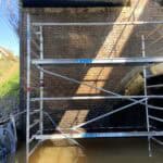 Stijger langs bakstenen brug boven water.