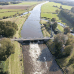 Luchtfoto van rivier met dam en omliggend landschap.