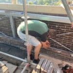 Metselaar werkt op steiger met bakstenen muur.