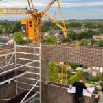 Bouwplaats met kraan en tekeningen op steiger.